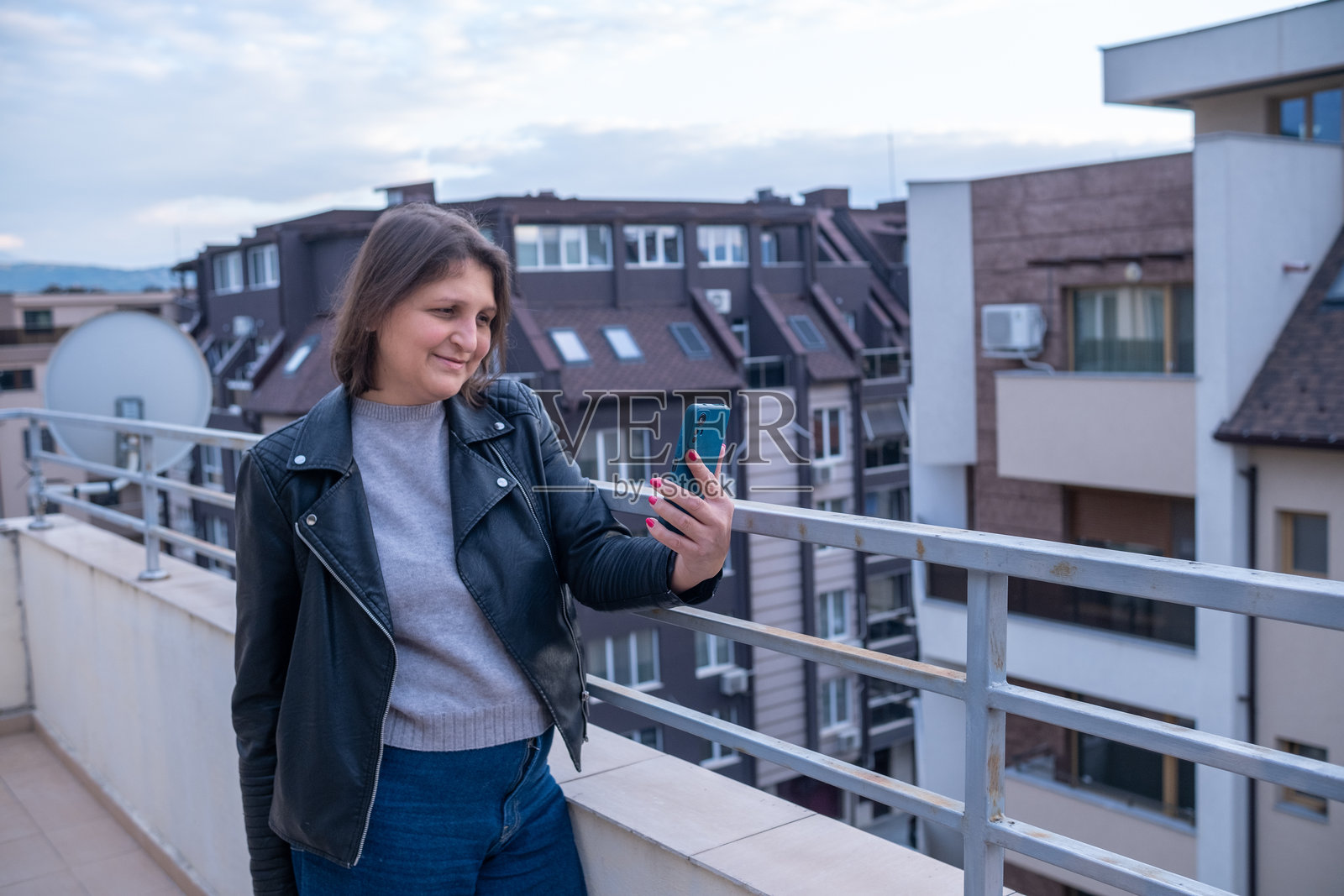 女性在城市阳台场景中使用智能手机照片摄影图片