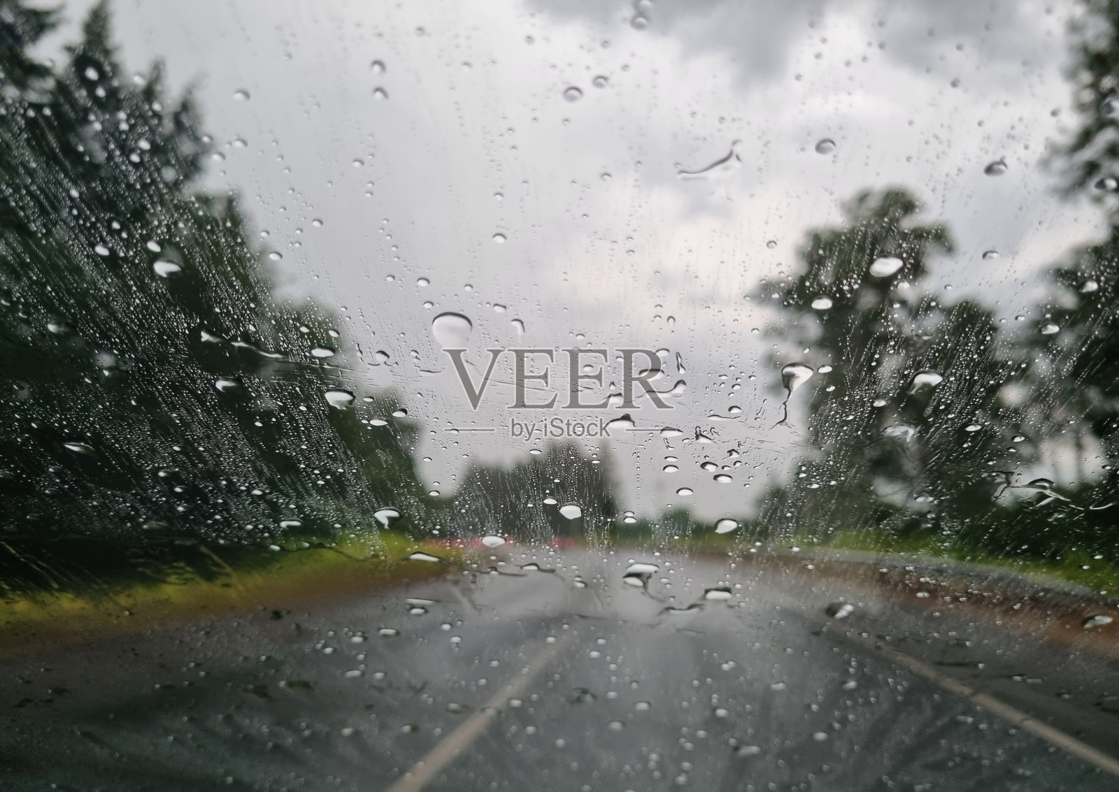 雨天的路。雨滴落在挡风玻璃上。照片摄影图片