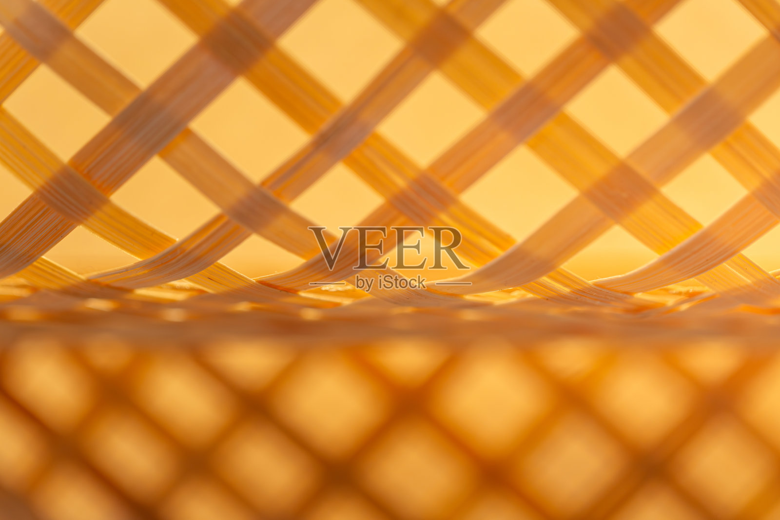 编织篮内部纹理的特写,带有交织图案和温暖的金色调照片摄影图片