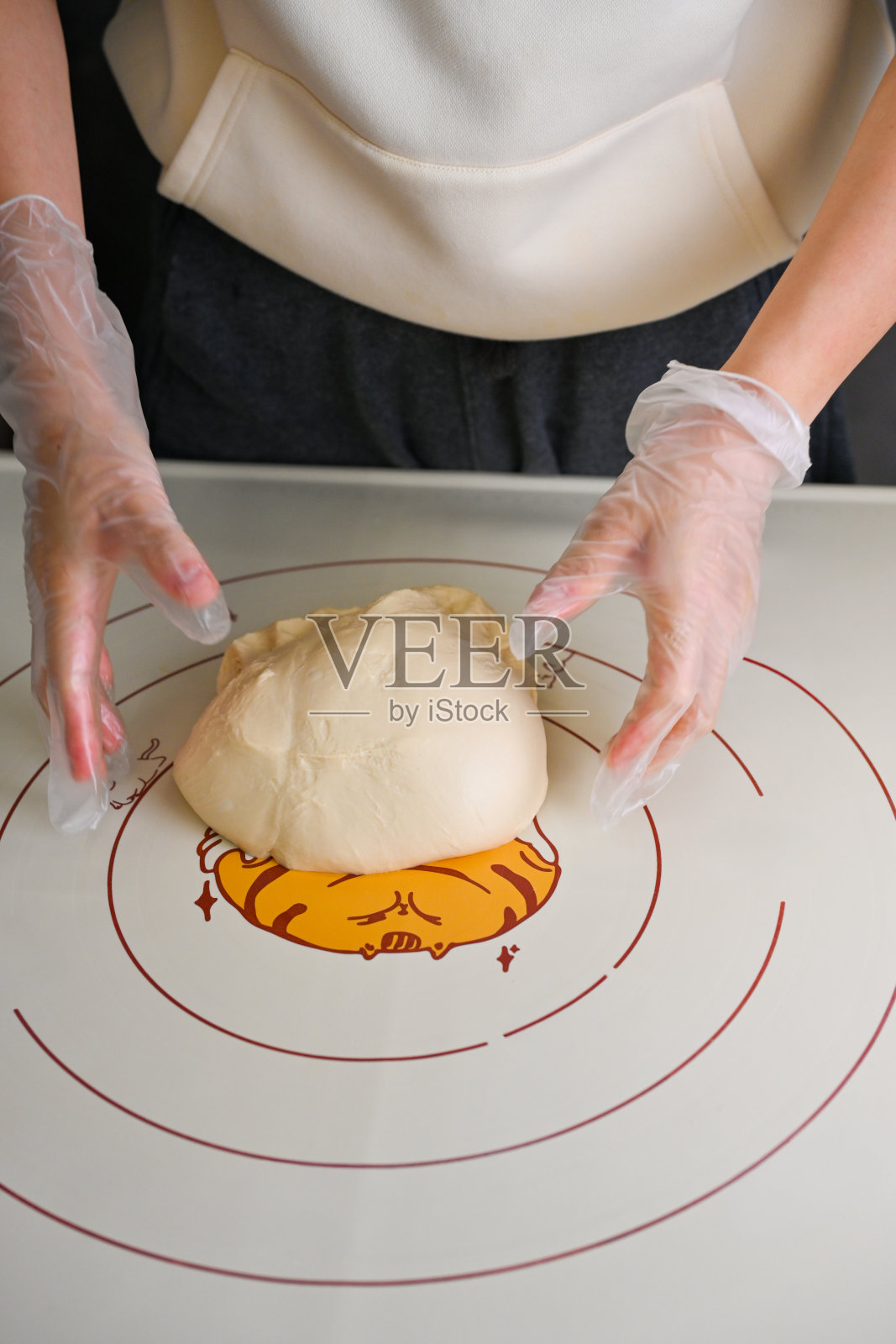 一个人戴着一次性手套,在装饰性的烘焙垫上揉面团照片摄影图片