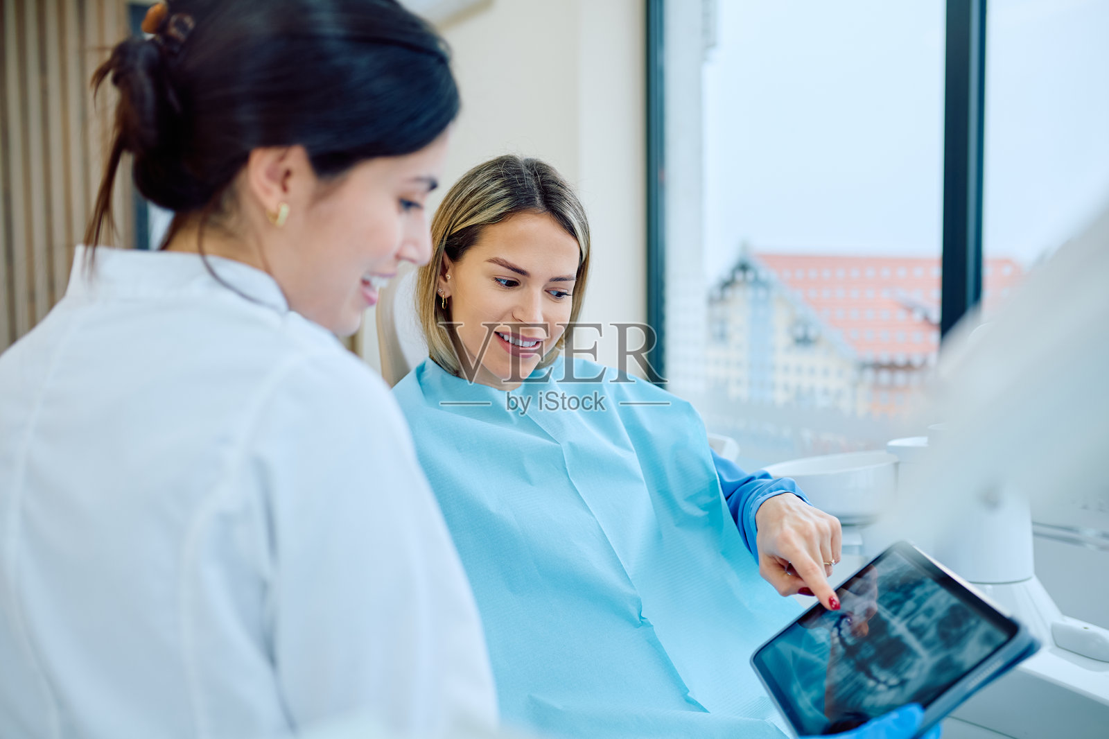 牙医在数字平板电脑上向患者展示牙科X光片照片摄影图片