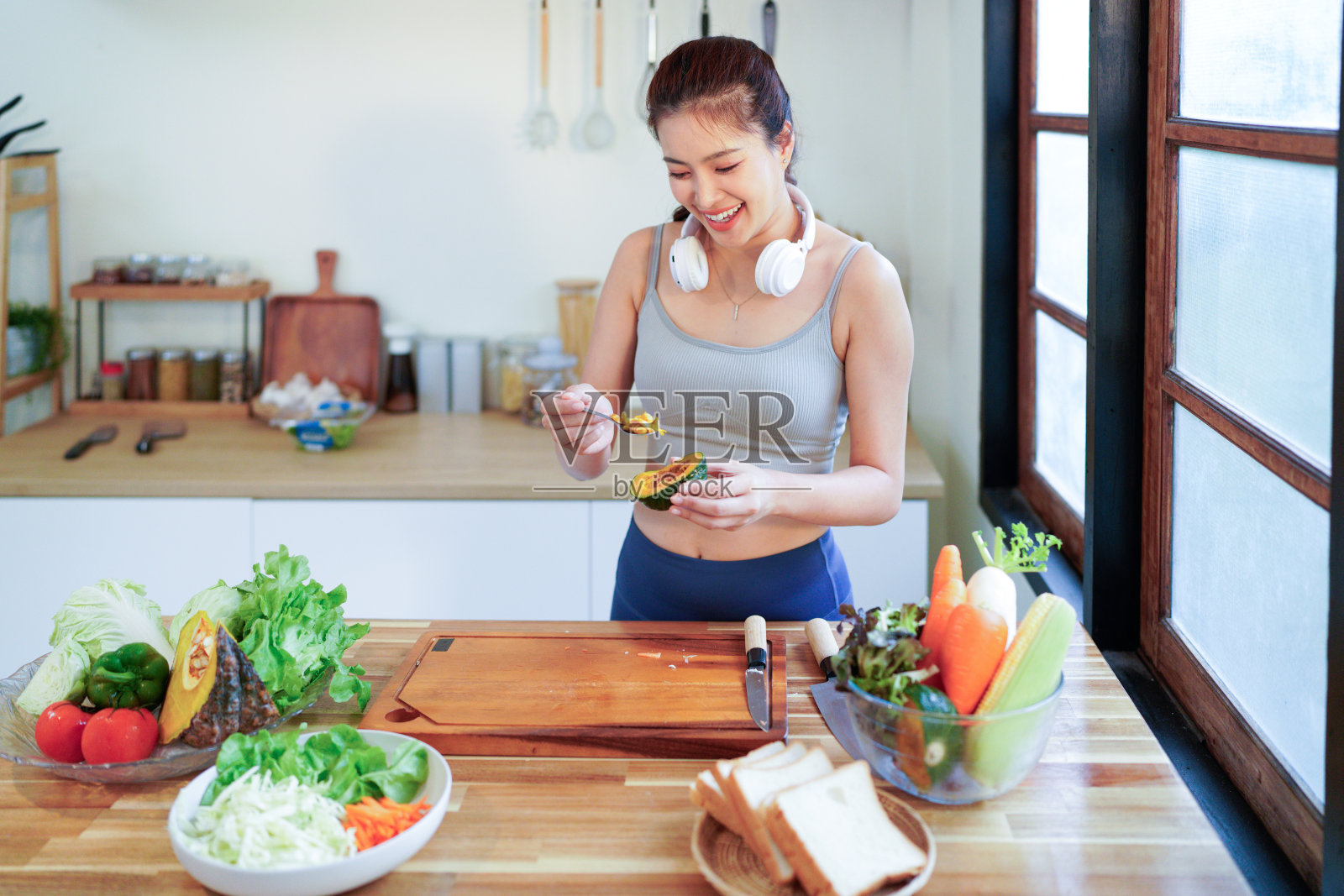 一位漂亮的女士穿着运动服在厨房里做沙拉照片摄影图片
