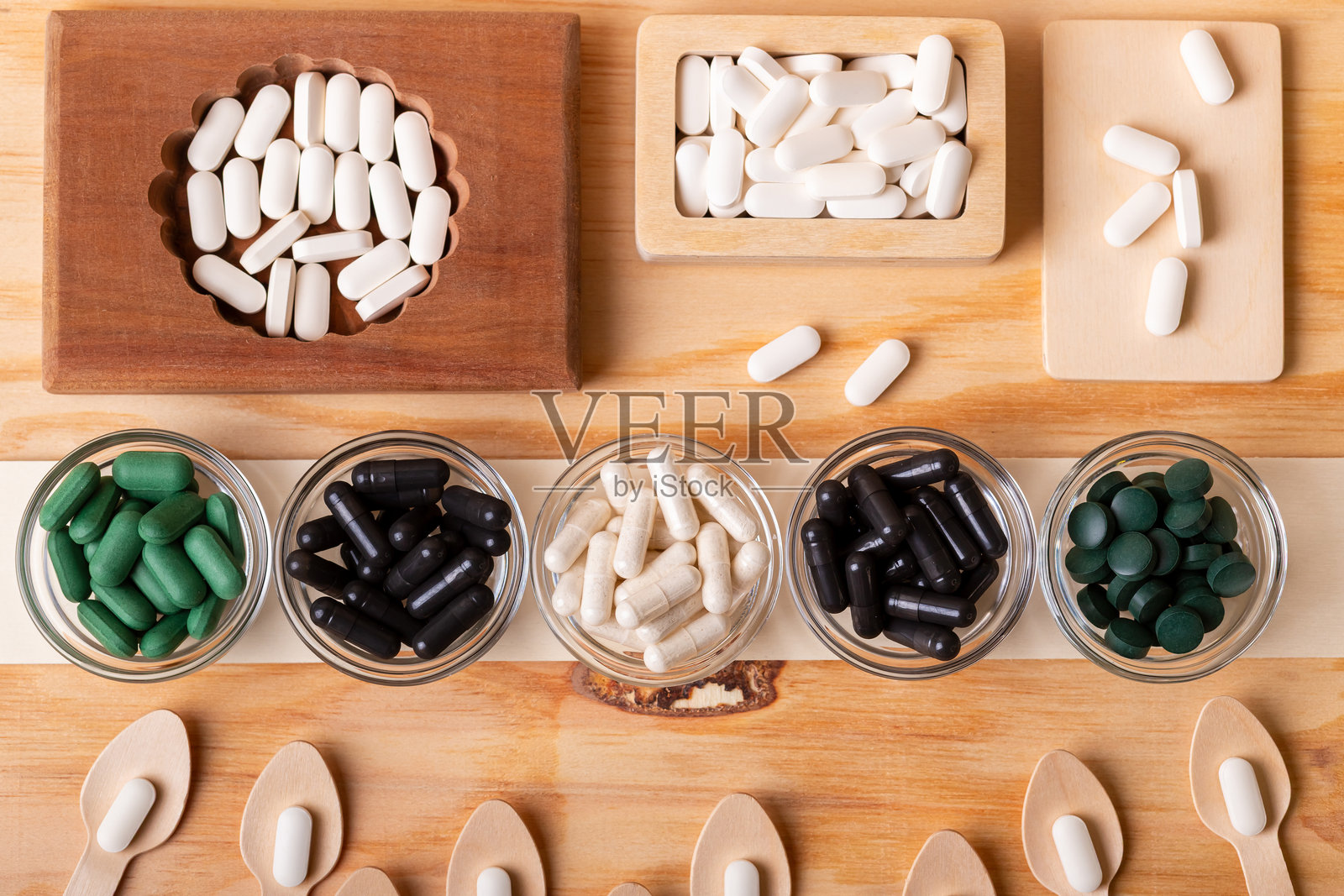 许多各种维生素、药片、膳食补充剂装在木盒和玻璃碗中,木勺里装着维生素。照片摄影图片