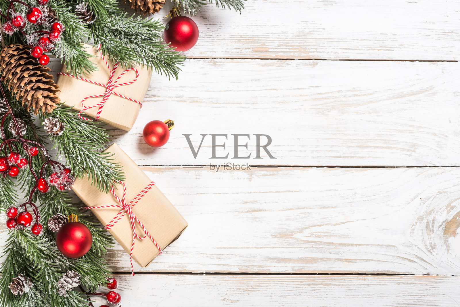 白桌上的冬青圣诞树,覆盖着雪,并饰有装饰品。照片摄影图片