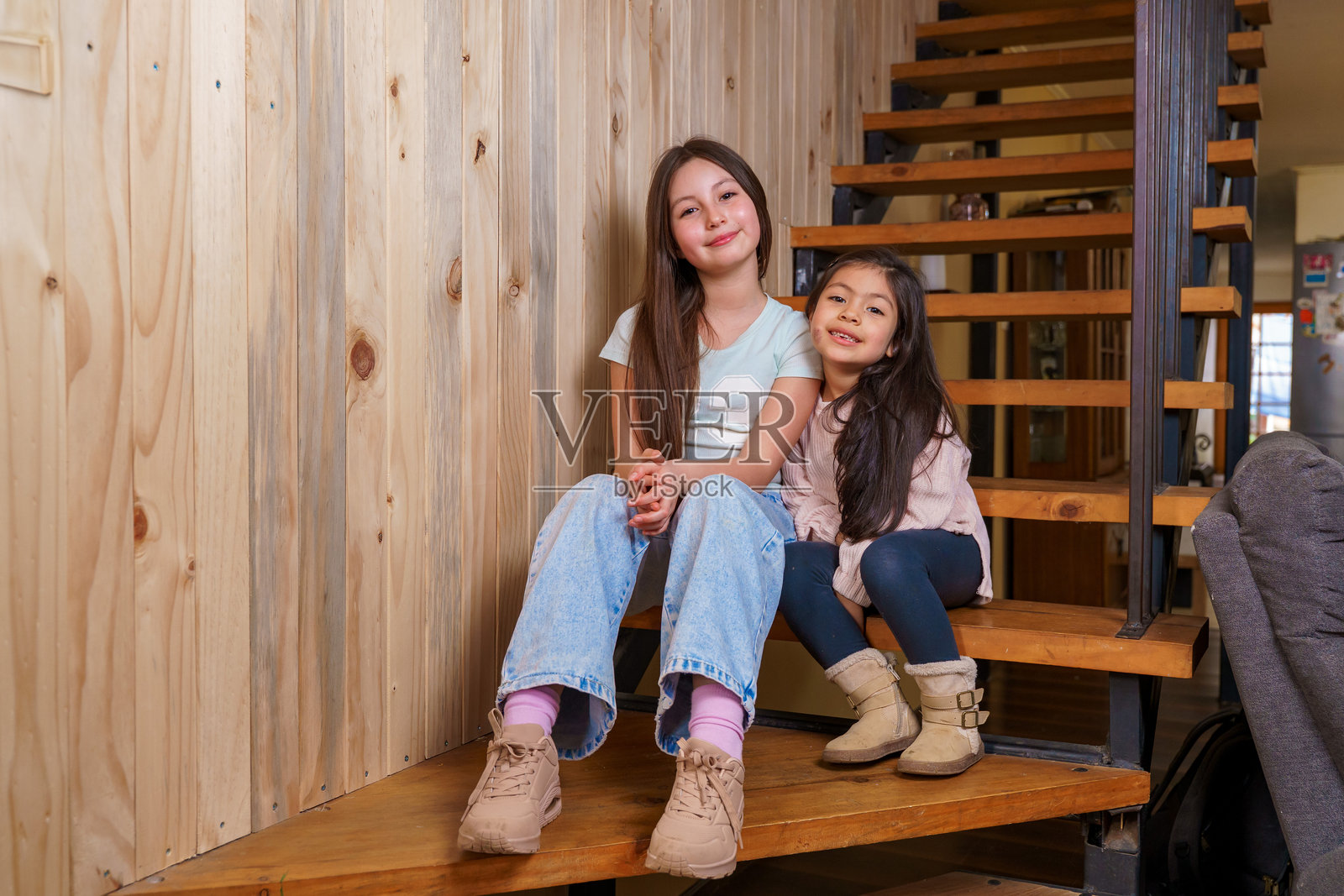 两个开心的女孩在家中的木质楼梯上坐着照片摄影图片