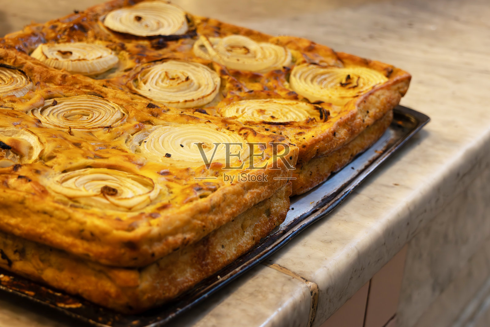 台面上的烤盘里放着金黄色的洋葱派照片摄影图片