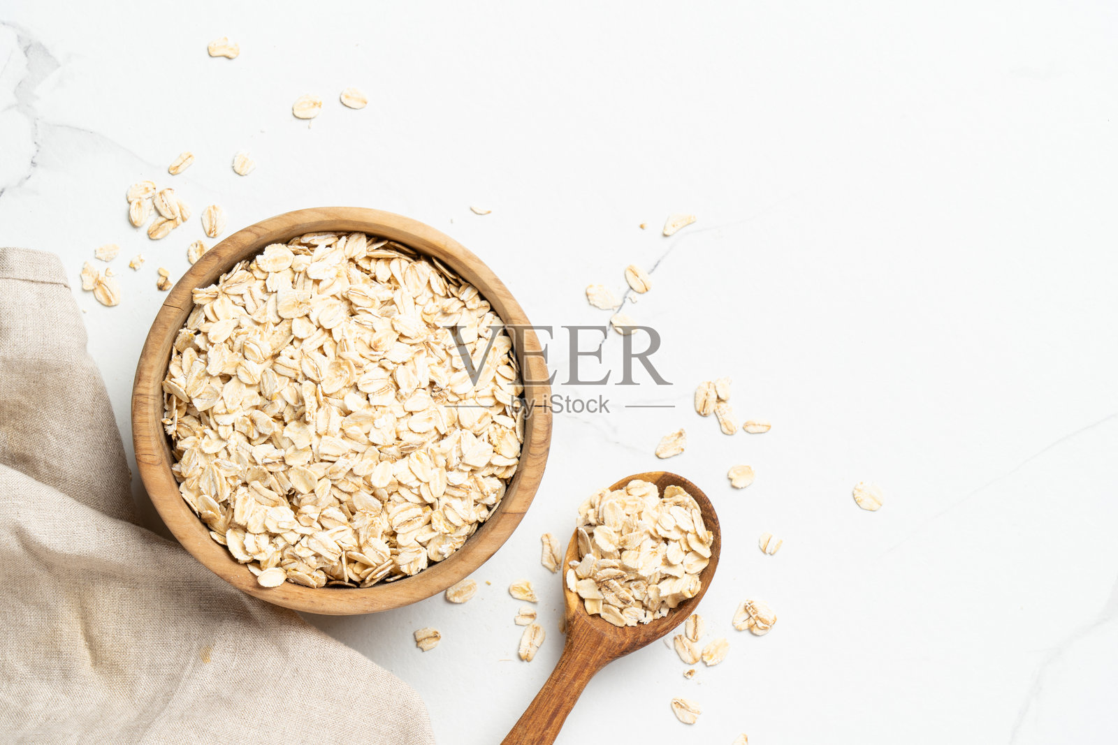 白色背景上,木碗里装着燕麦片。照片摄影图片