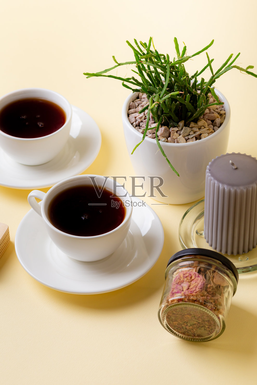 米色背景上的茶杯、茶叶、盆栽植物和蜡烛照片摄影图片