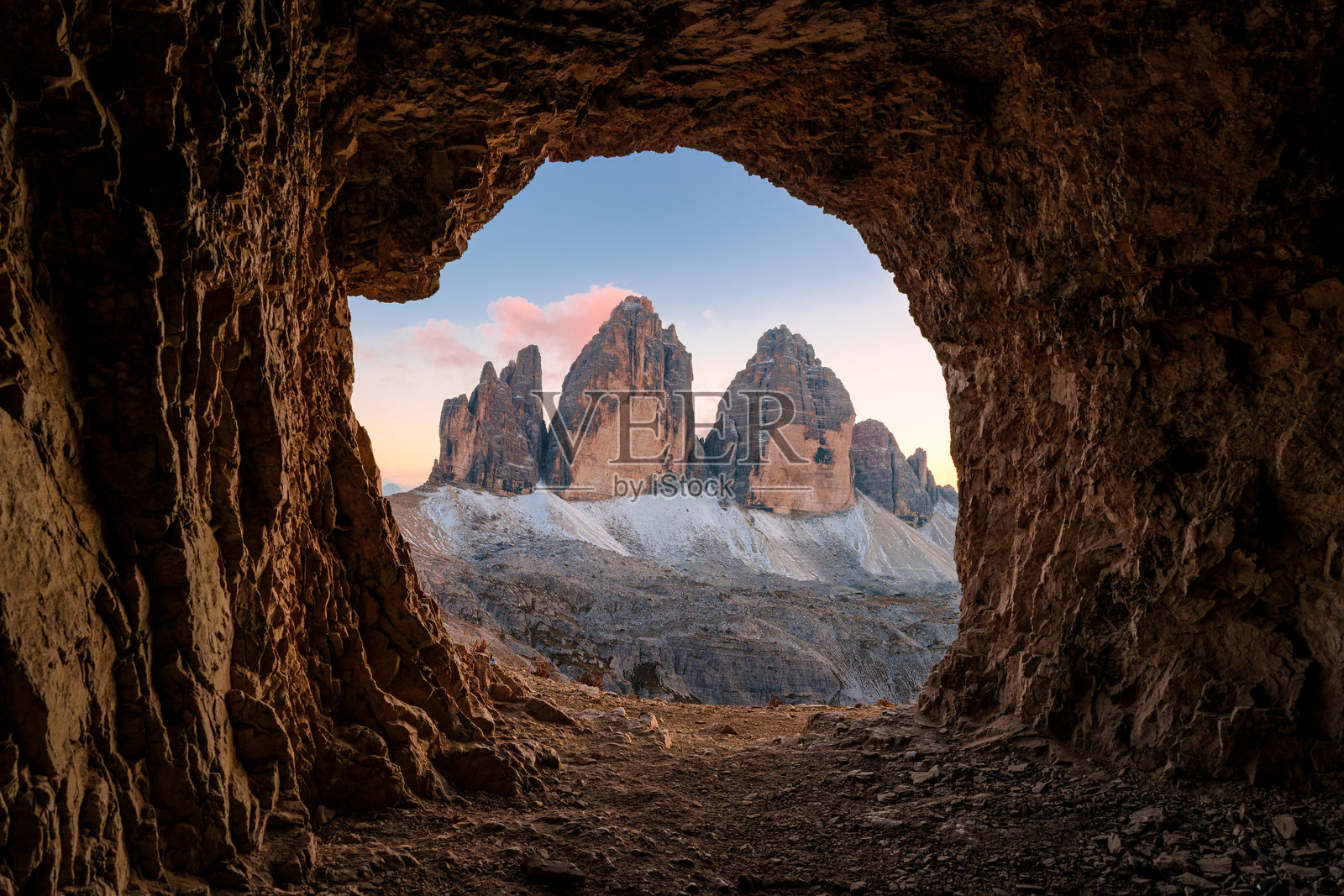 意大利多洛米蒂山脉,三尖峰的岩石隧道(Grotta delle Tre Cime)在落日时分映衬着三尖峰(Tre Cime di Lavaredo)的山峰照片摄影图片
