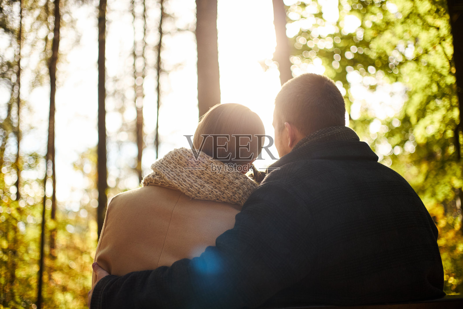 日落时分,年轻情侣在秋季的森林里依偎而坐照片摄影图片