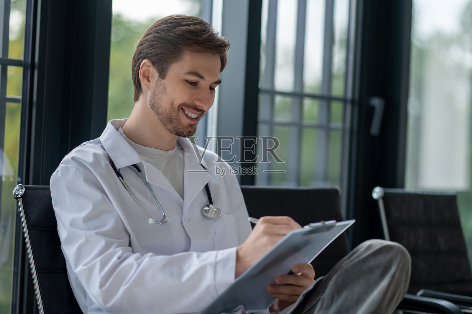 医生戴着听诊器在文件夹上写字照片摄影图片