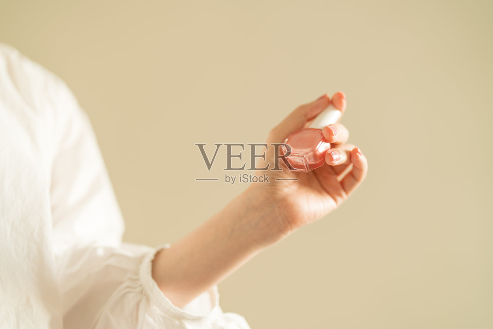 女士的手拿着粉色指甲油照片摄影图片