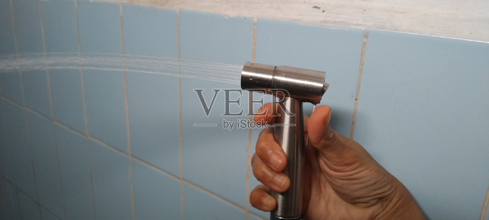 手持铬合金喷枪式洁身器,坐在马桶上照片摄影图片