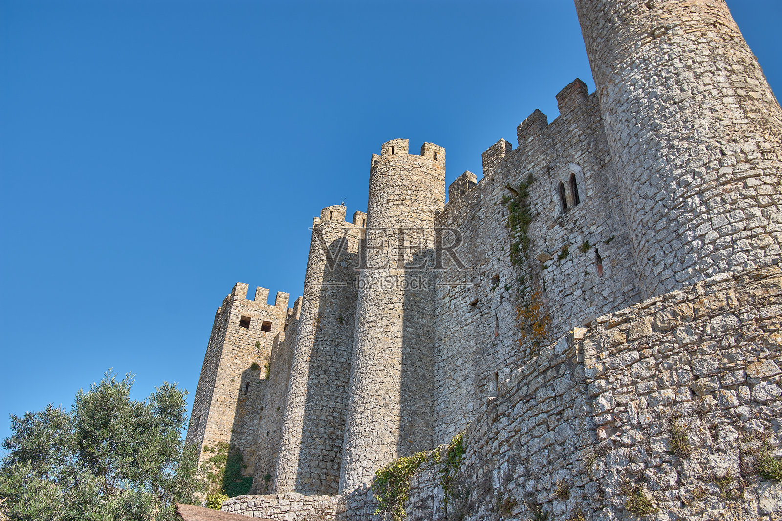 葡萄牙历史遗产背景下的奥比杜什中世纪城墙,配有圆柱形塔楼和蓝天。照片摄影图片