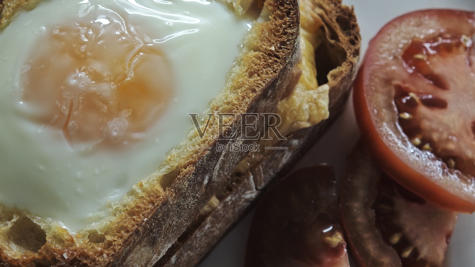 一片面包里煎熟的鸡蛋,配上新鲜的番茄片照片摄影图片