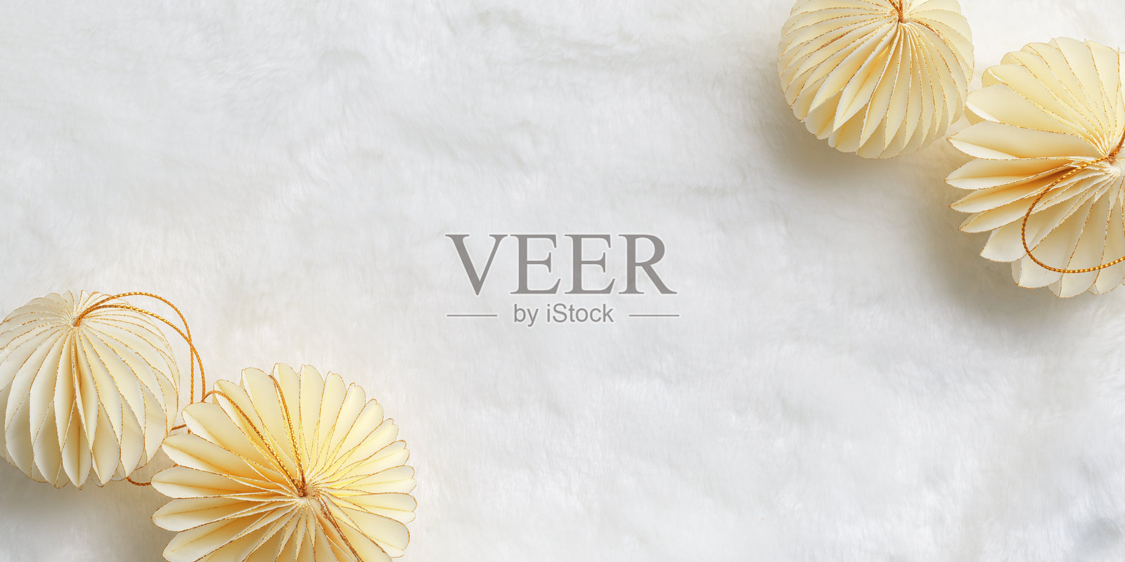 简约风格的冬日假期俯视图,有新年纸质节日装饰品、奶油米色圣诞球,背景为白色人造毛皮纹理,附有复制空间。中性色调,柔和阴影。照片摄影图片