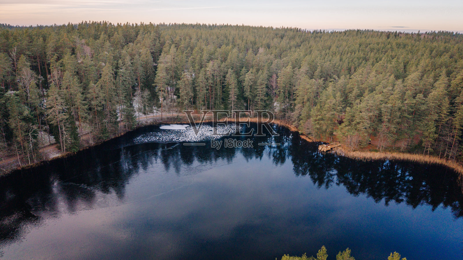 茂密常绿森林环绕的宁静湖泊的航拍图,湖面映照着天空和树木,营造出宁静祥和的自然景观照片摄影图片