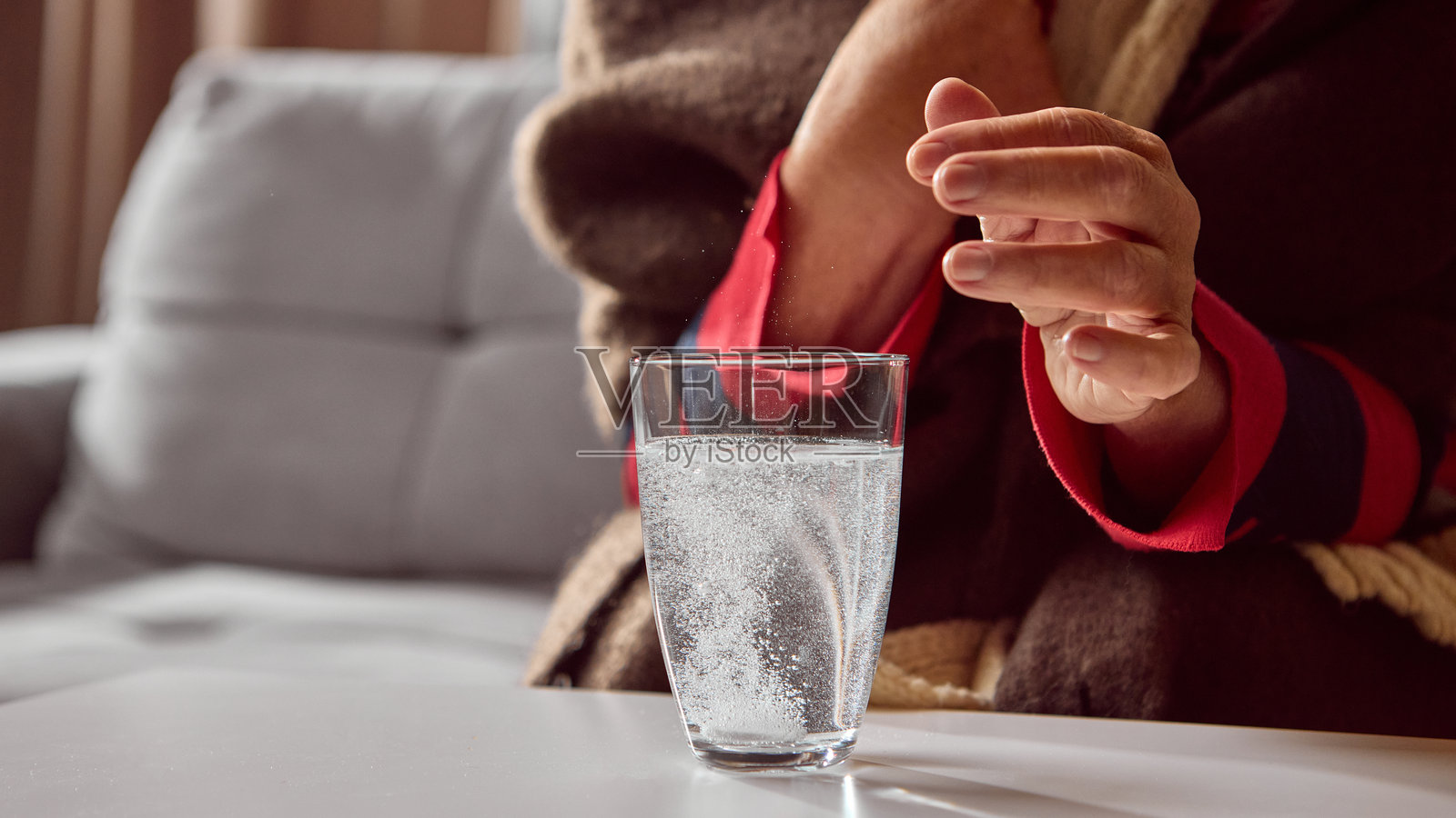 一位老年妇女看着泡腾片在水中溶解照片摄影图片