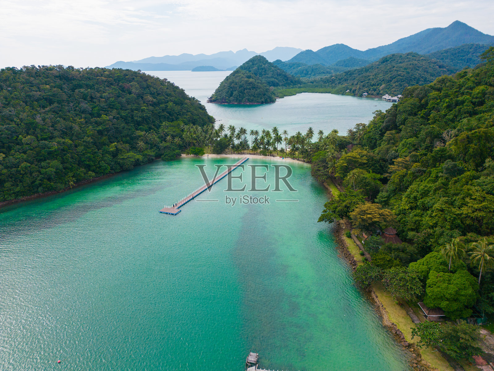 从上方俯瞰,热带棕榈树伫立在沙滩上,碧绿的海水环绕。照片摄影图片