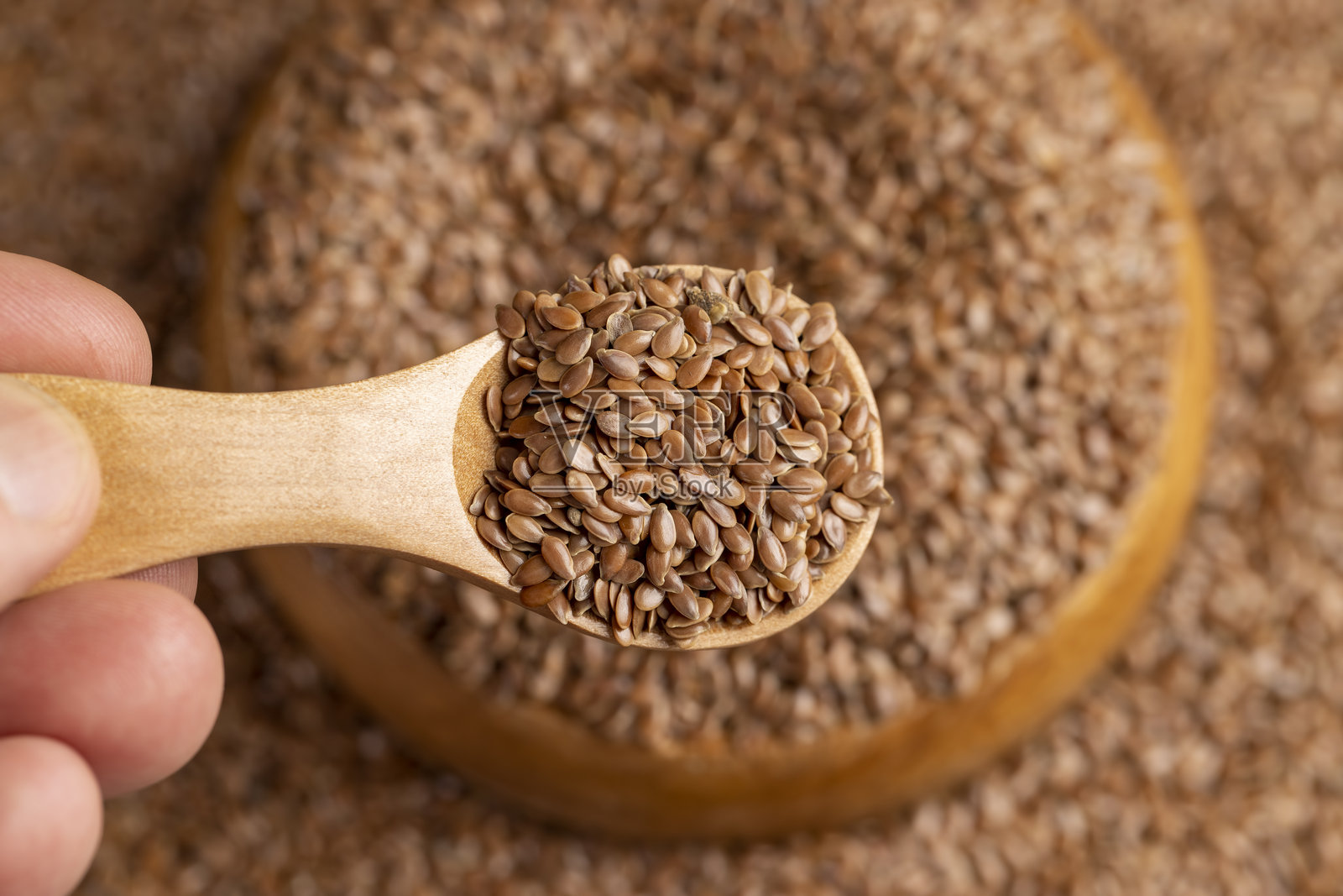 亚麻籽倒入木碗中,圆木碗装满了亚麻籽,可用于营养和收获照片摄影图片