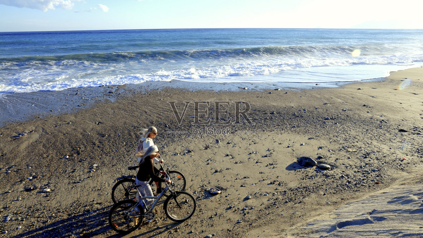 日落时分,成熟的女性在海滩上骑自行车照片摄影图片
