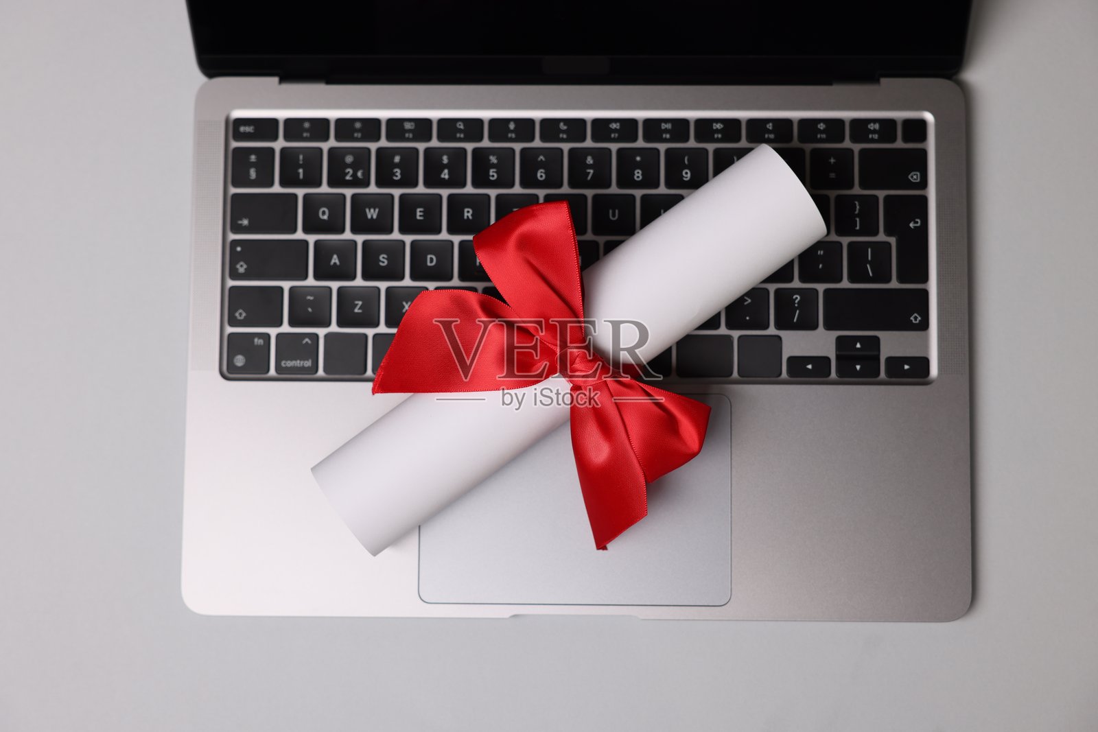 浅色桌子上的文凭和笔记本电脑,俯视角度照片摄影图片