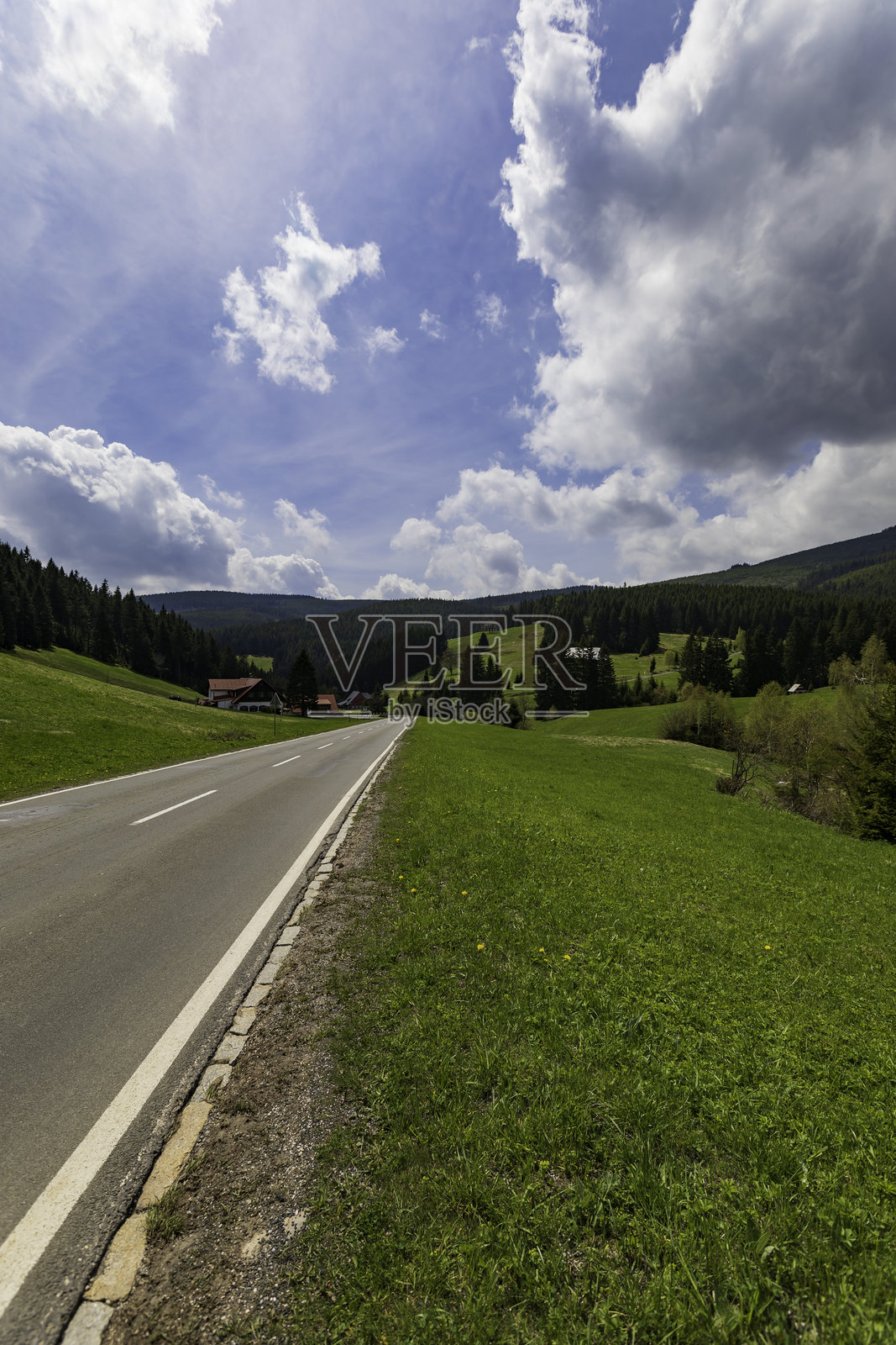 蓝天下的田园风光,一条乡村公路蜿蜒穿过绿色的山丘照片摄影图片