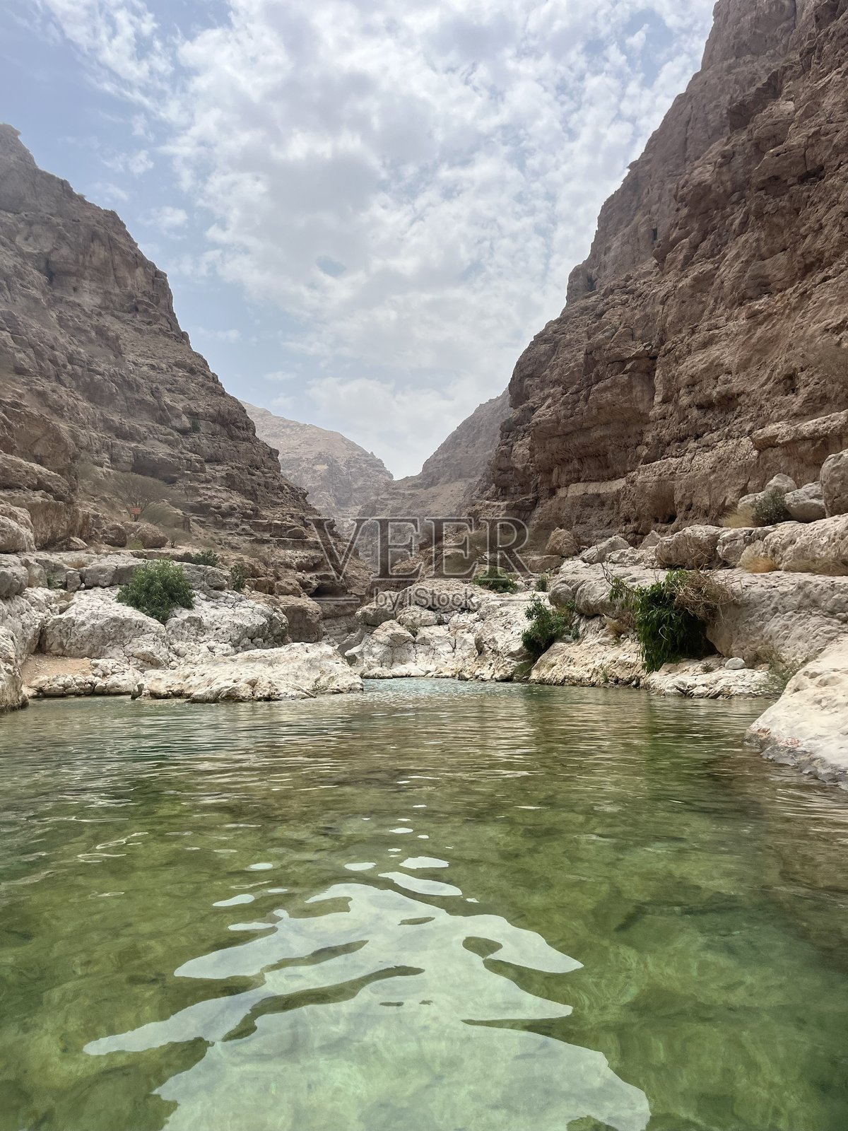 陡峭悬崖下的沙漠峡谷中的河流和岩石水池照片摄影图片