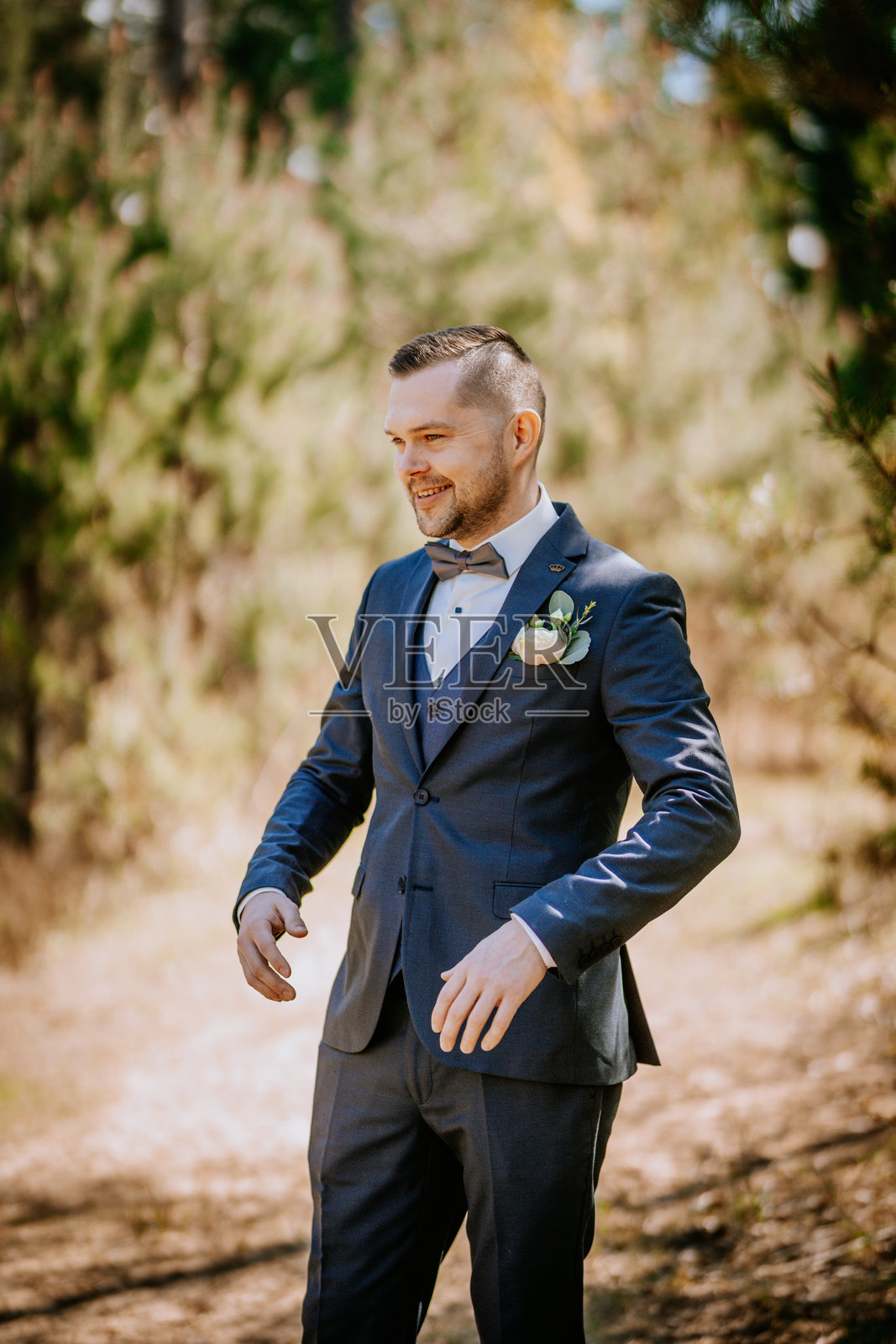 身着定制西装、打着领结的时尚男士,在郁郁葱葱的自然户外环境中开怀大笑,捕捉庆祝与优雅的瞬间照片摄影图片