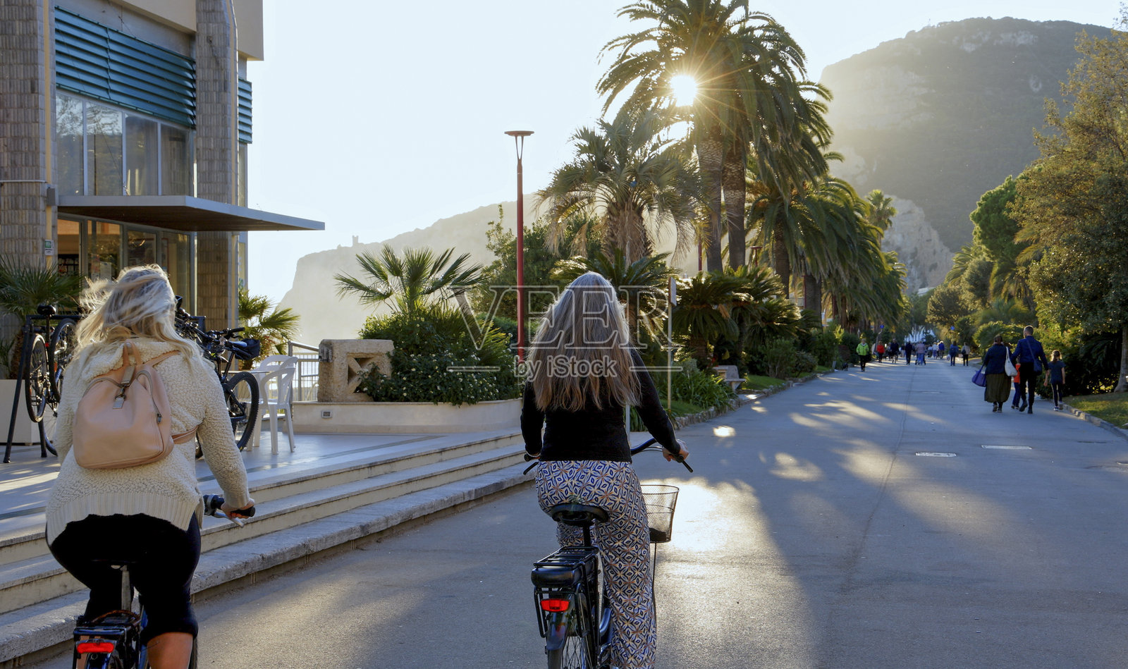 日落时分,成熟的女性在海滨大道上骑自行车照片摄影图片