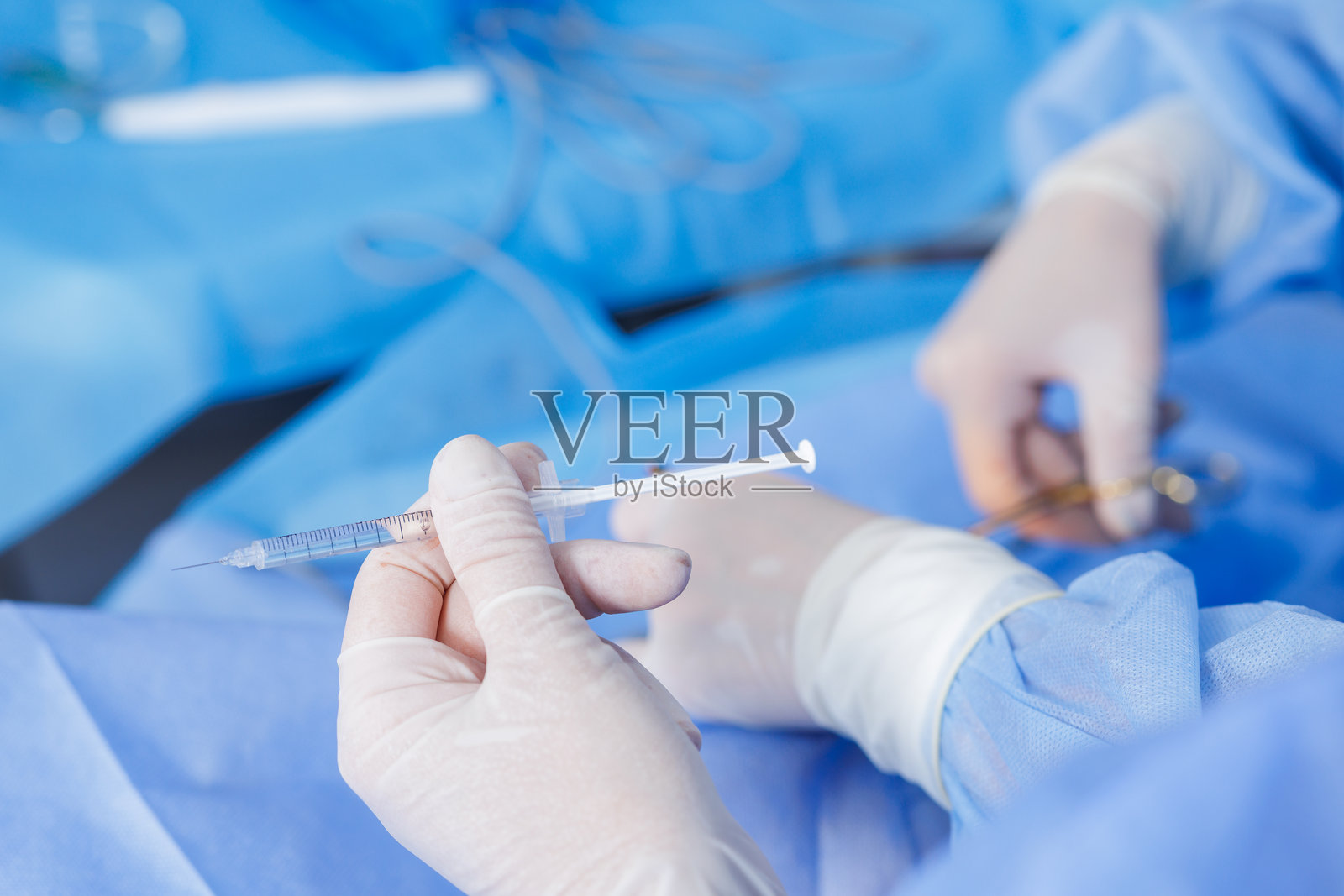 在无菌手术室操作过程中,戴着手套的手中拿着注射器,内含麻醉剂照片摄影图片