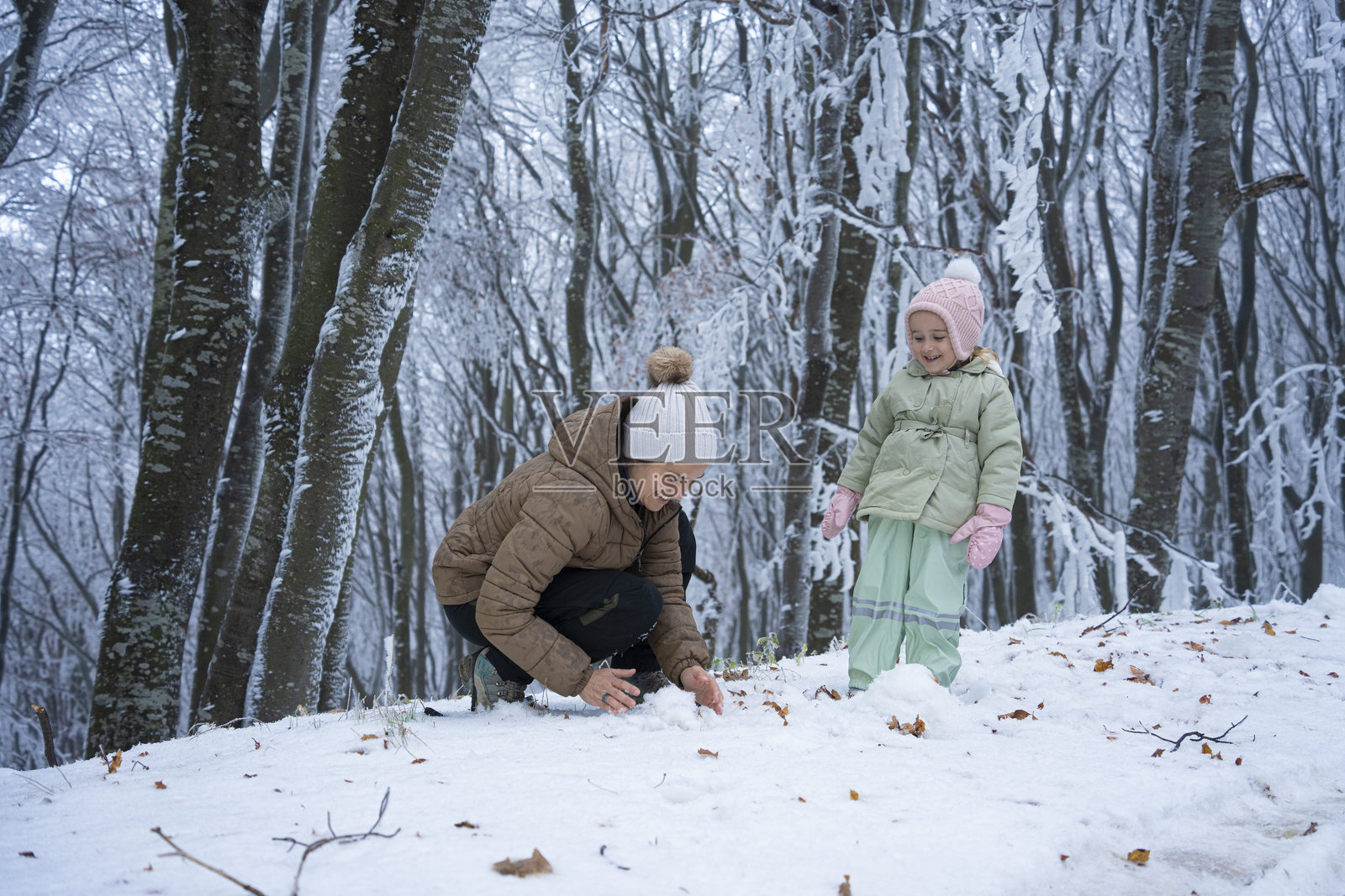 一家人打雪仗,迎接初雪。妈妈和孩子享受冬日乐趣。照片摄影图片
