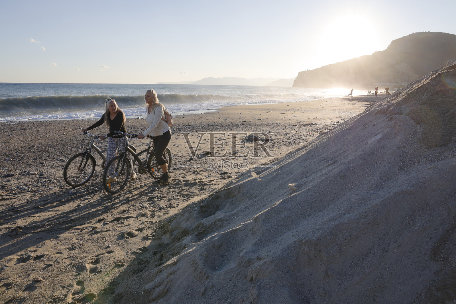 成熟的女性在日落时分于海滩骑行照片摄影图片