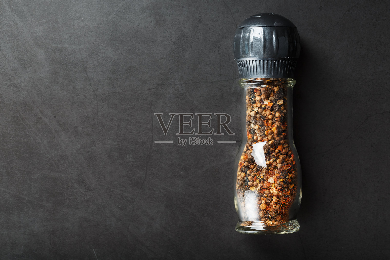 黑色背景下,玻璃研磨罐中盛有多种调味料、香料和香草。照片摄影图片