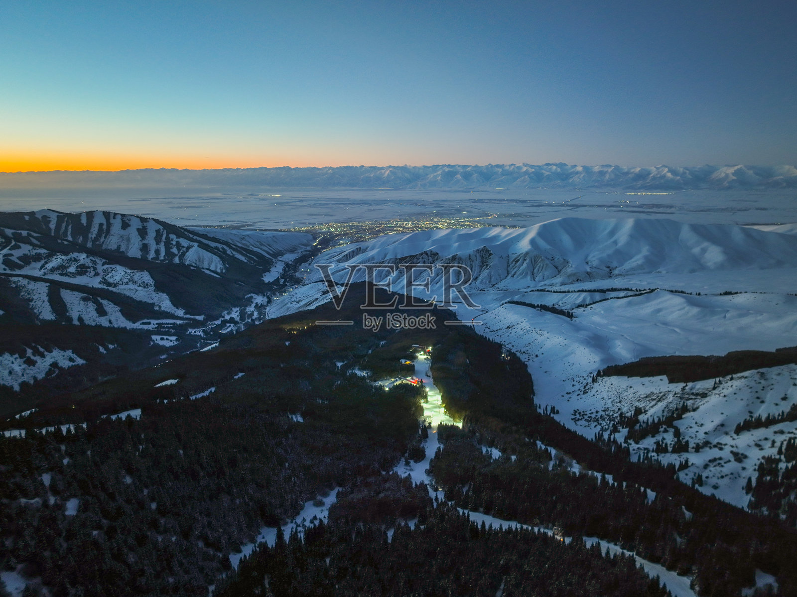 蓝色时分的灯光点缀的滑雪场和卡拉科尔市的灯火照片摄影图片