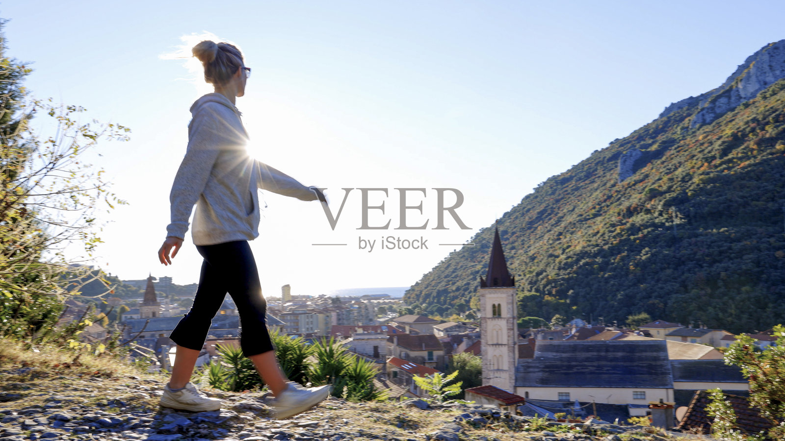 日出时分,年轻女子站在山顶俯瞰村庄,位于利古里亚照片摄影图片