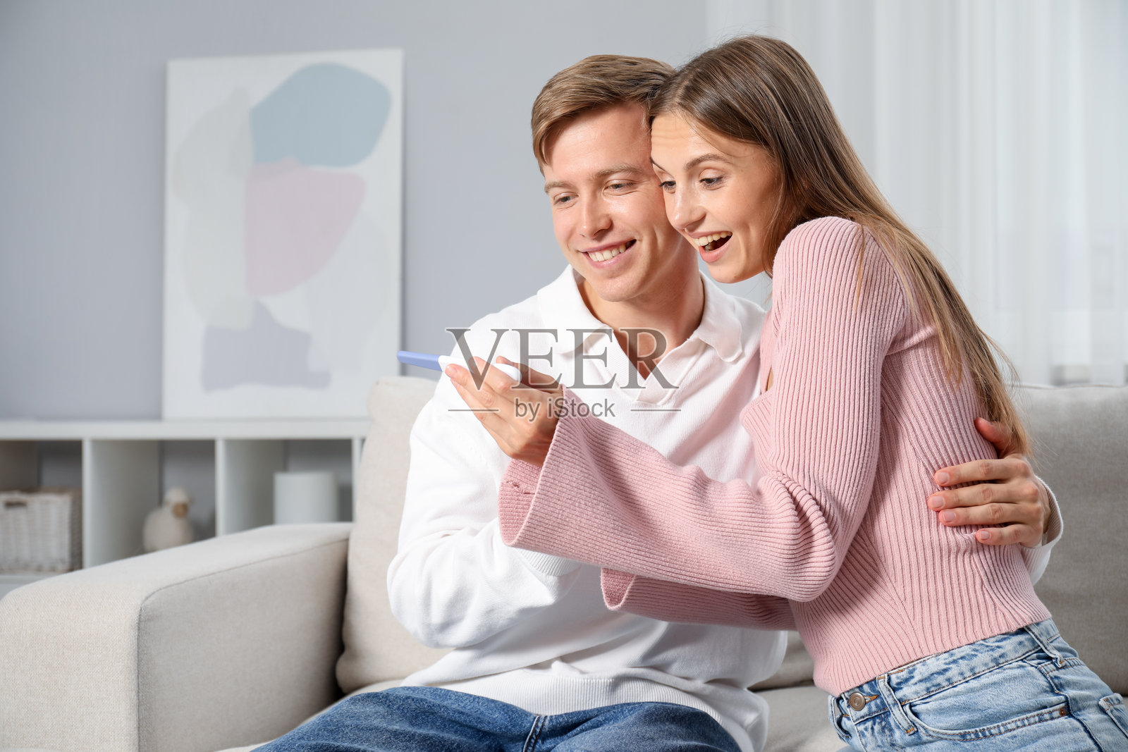 快乐的夫妇在家里的沙发上拿着验孕棒照片摄影图片