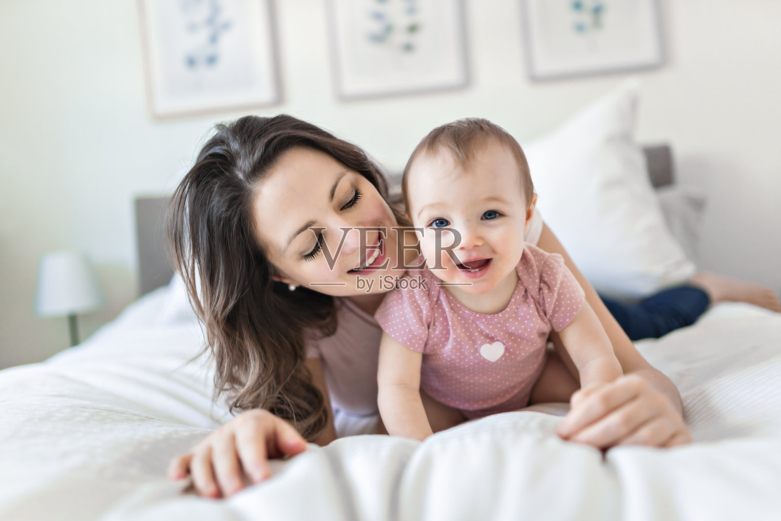 快乐的一家人。妈妈和宝宝在毯子下玩耍,面带笑容照片摄影图片