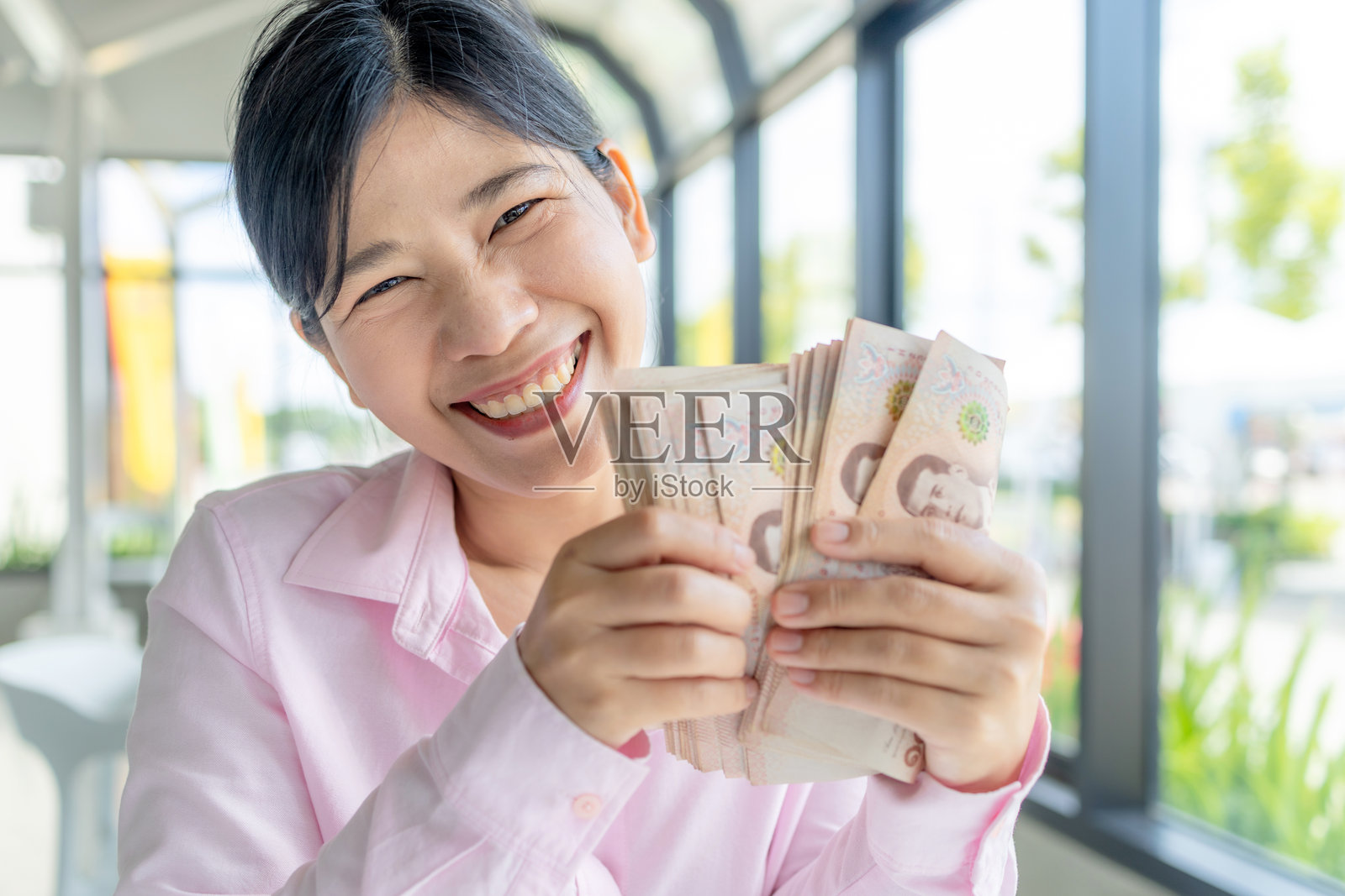 钱,现金,财富,快乐的亚洲女性手持泰铢纸币,展示财富、成功和财务幸福,特写照片摄影图片