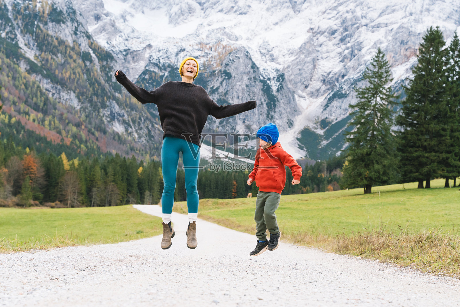 一家人在大自然中徒步旅行。一位母亲带着儿子在秋季的山景道路上奔跑。母子户外时光。亲子户外探险旅行。照片摄影图片