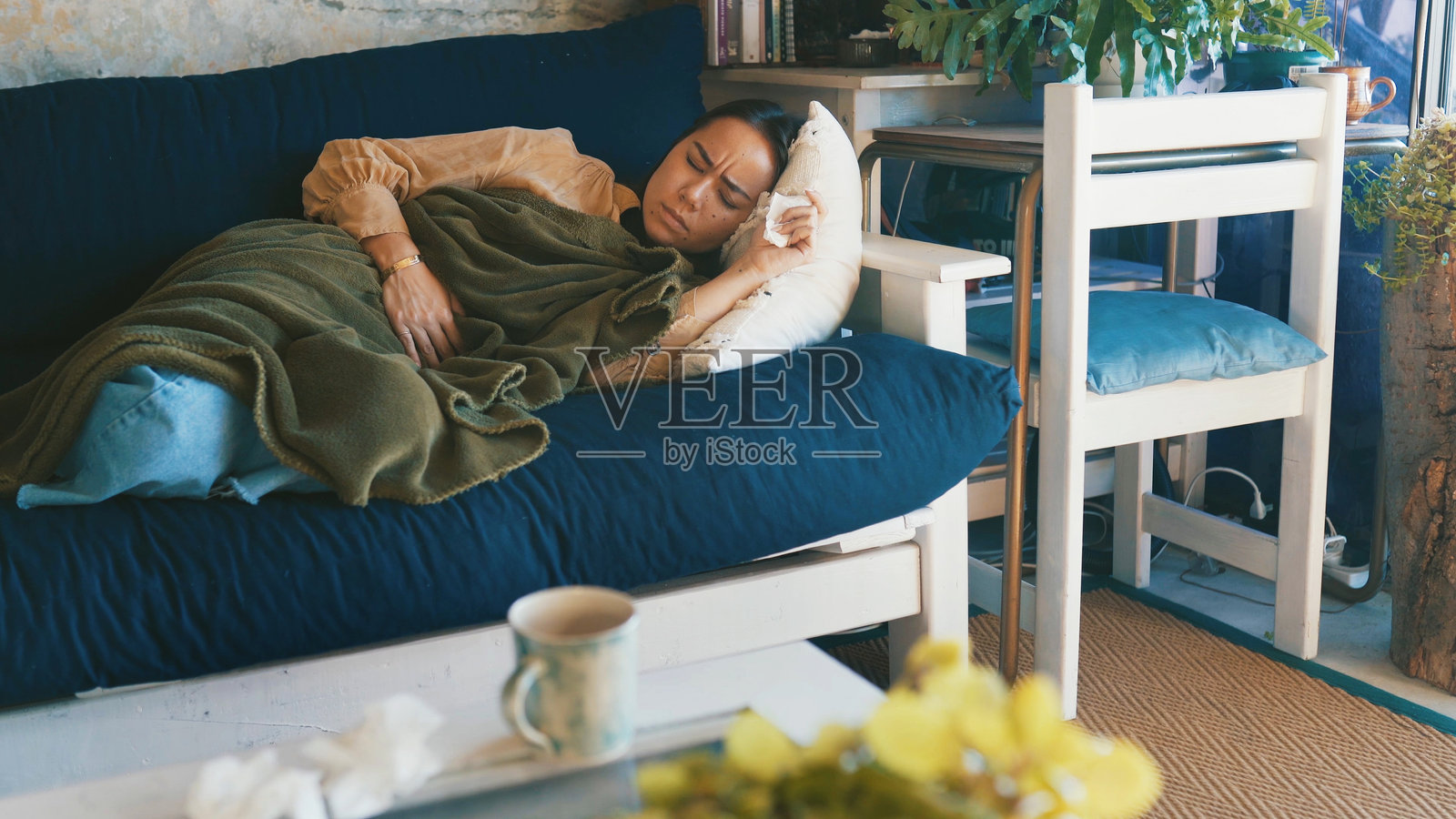 家中,女子躺在沙发上,胃痛、痛经,在客厅。公寓,腹痛、病毒感染,休息中,患有肠易激综合征和便秘、子宫内膜异位症和消化不良。照片摄影图片