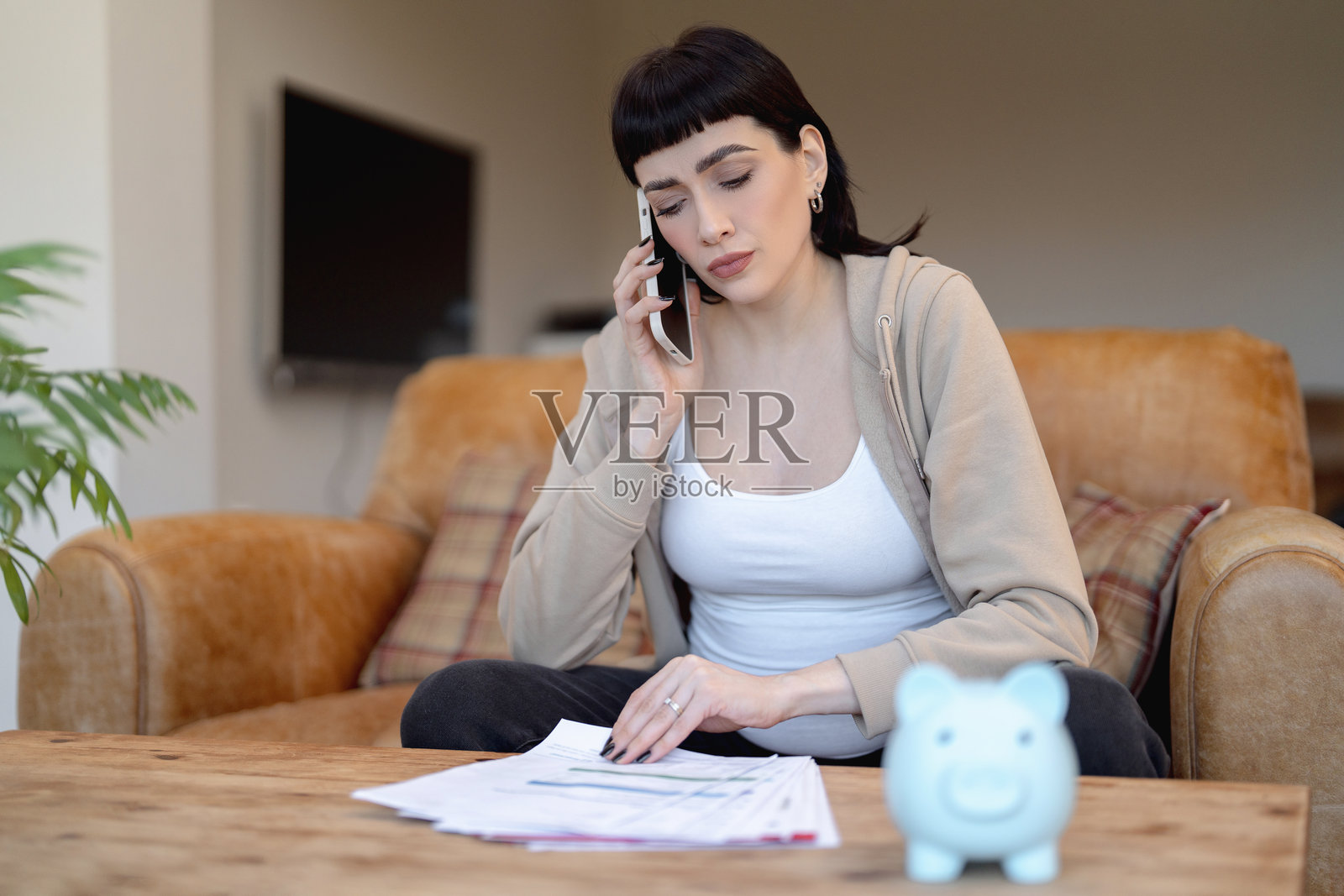 一位女士在舒适的客厅环境中,通过电话讨论财务问题照片摄影图片