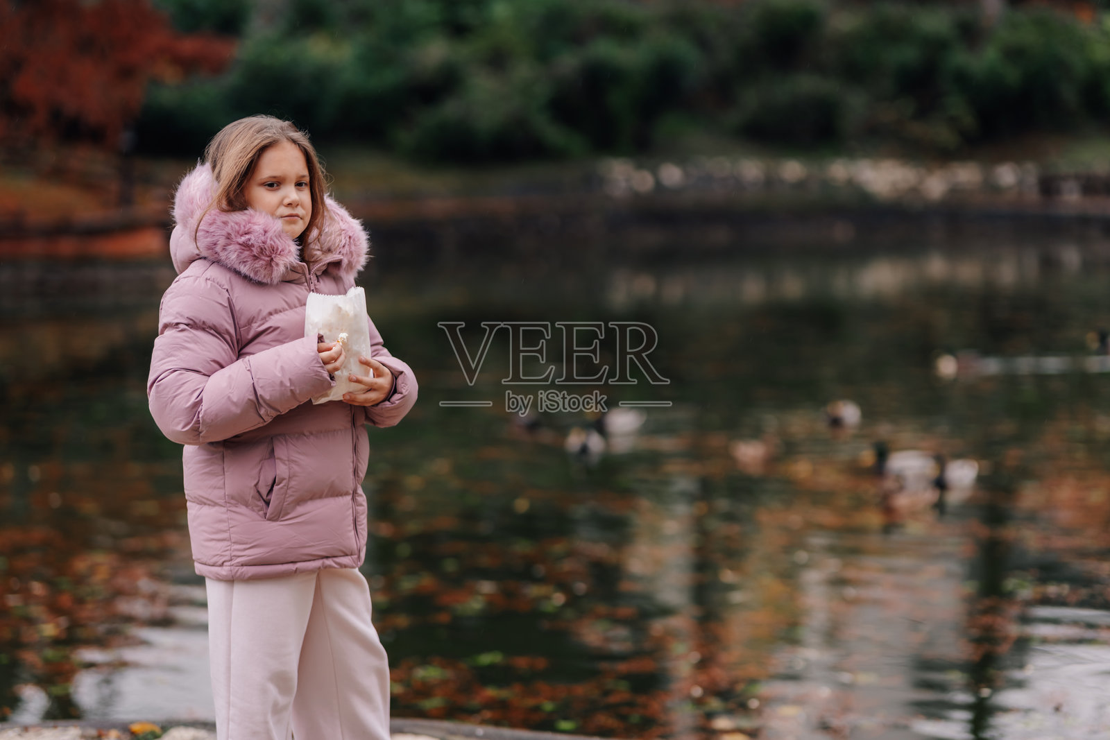 秋日公园湖边,女孩提着食品袋照片摄影图片