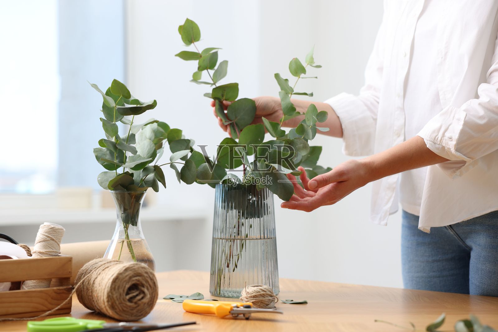 花艺师在花店的木桌上制作漂亮的桉树枝花束,特写照片摄影图片
