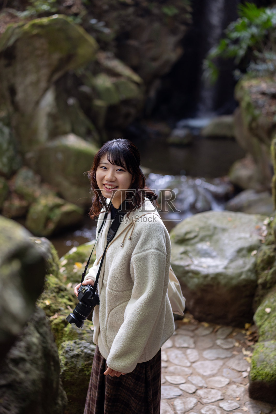 年轻的女游客在瀑布前回望照片摄影图片