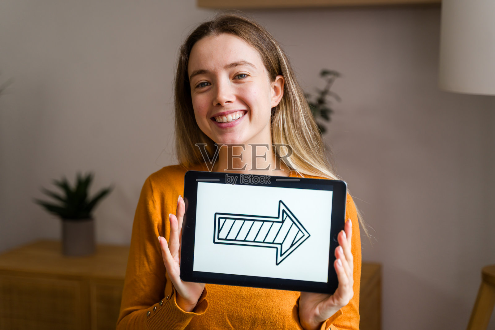 年轻女子展示平板电脑,上面有向右的指示箭头照片摄影图片