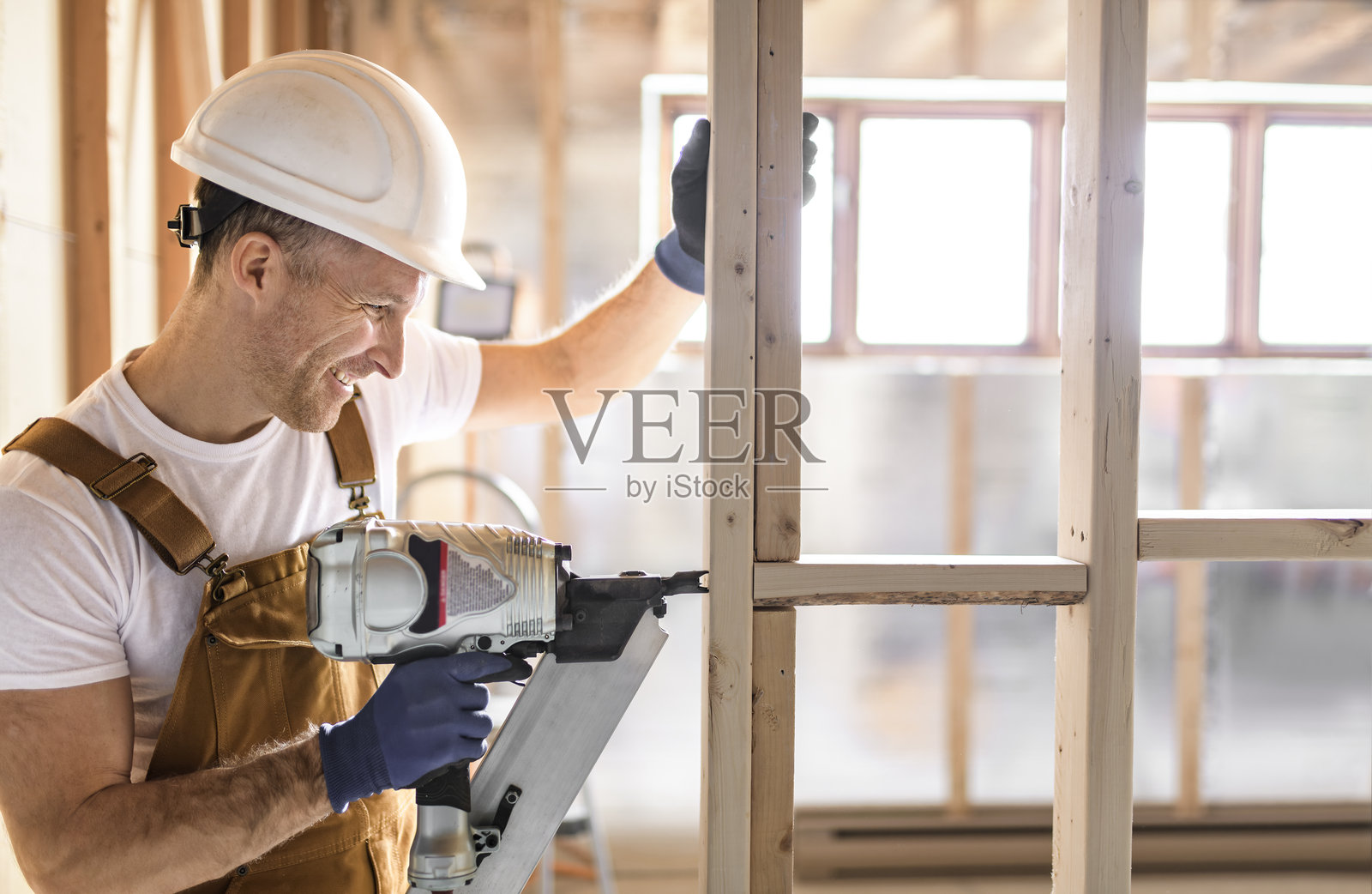 工人使用钉枪建造地下室房间照片摄影图片