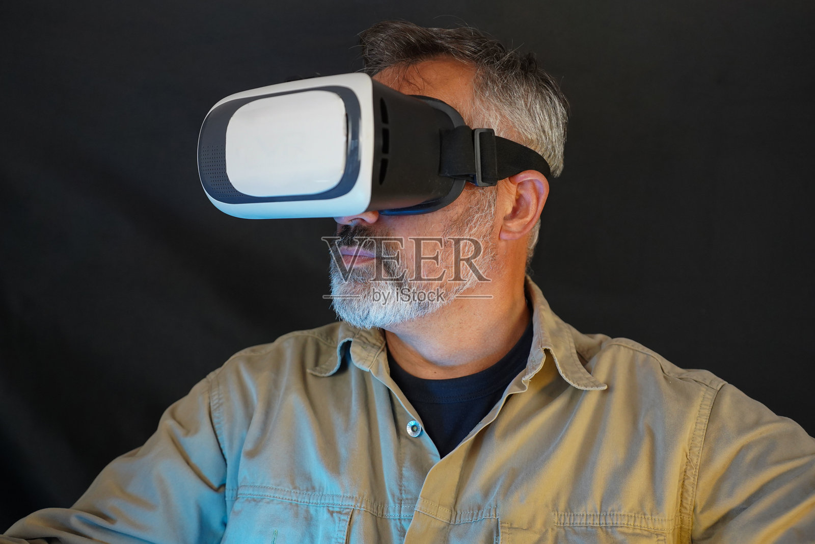 一位老年男子戴着VR眼镜,背景为黑色照片摄影图片