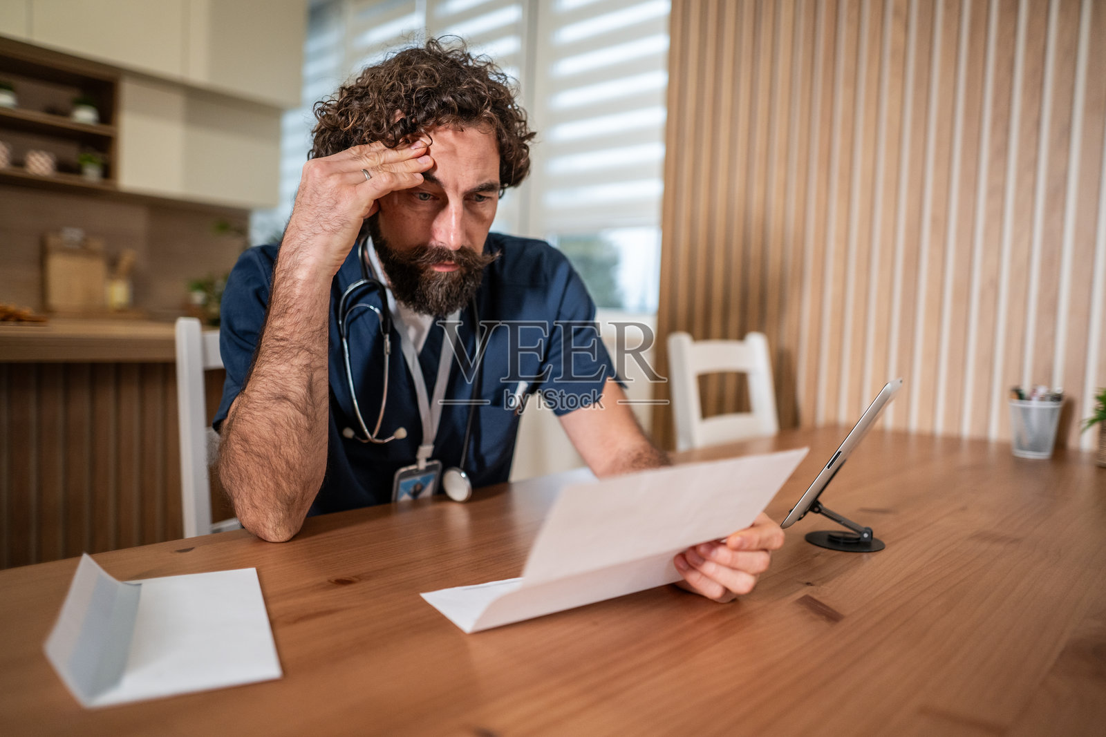 一名压力巨大的医生在家分析账单照片摄影图片