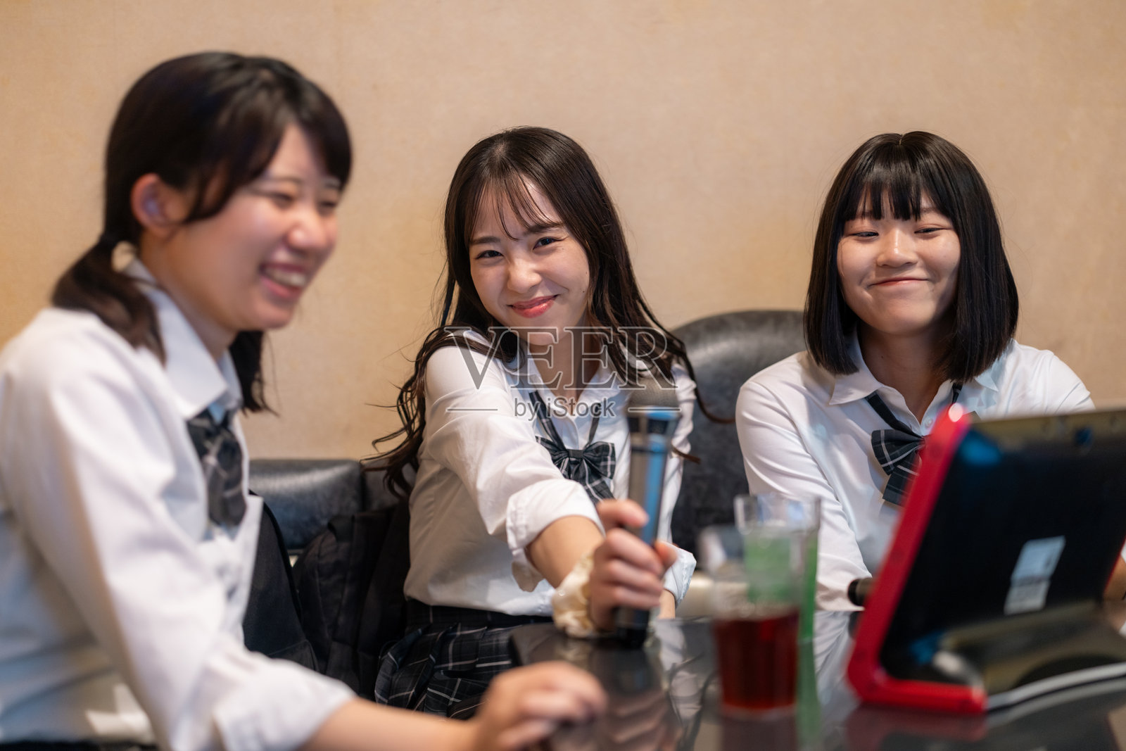 女高中生在KTV包间里开心唱卡拉OK照片摄影图片